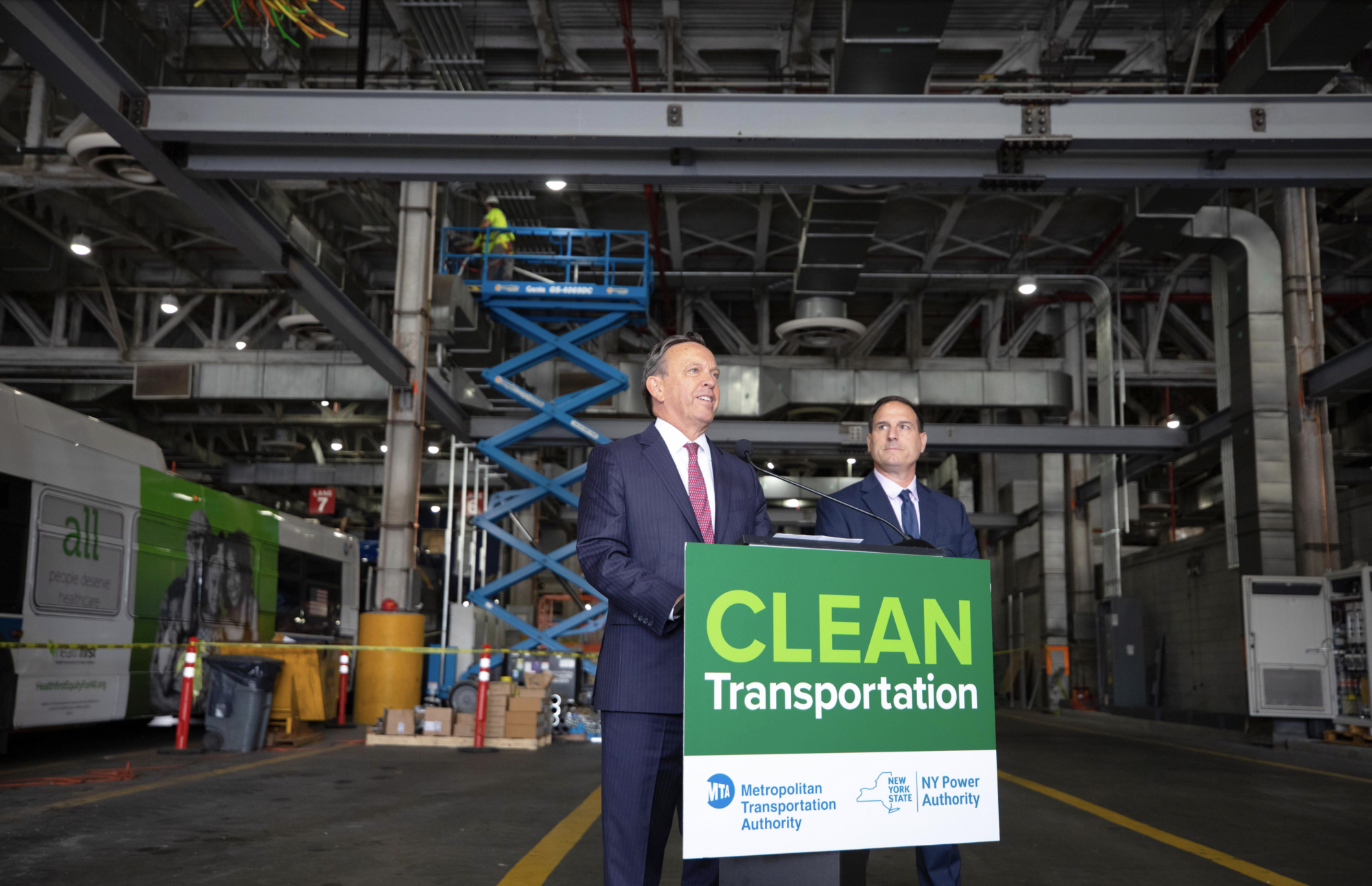 2023年9月22日、パンタグラフ式充電器が設置されたMTAのクイーンズ車庫にて。ニューヨーク州電力公社（NYPA）社長代行兼CEOのジャスティン・E・ドリスコル氏（左）とニューヨーク州都市交通局（MTA）のバス担当上級副社長であるフランク・アニカロ氏（右）(写真：New York State)
