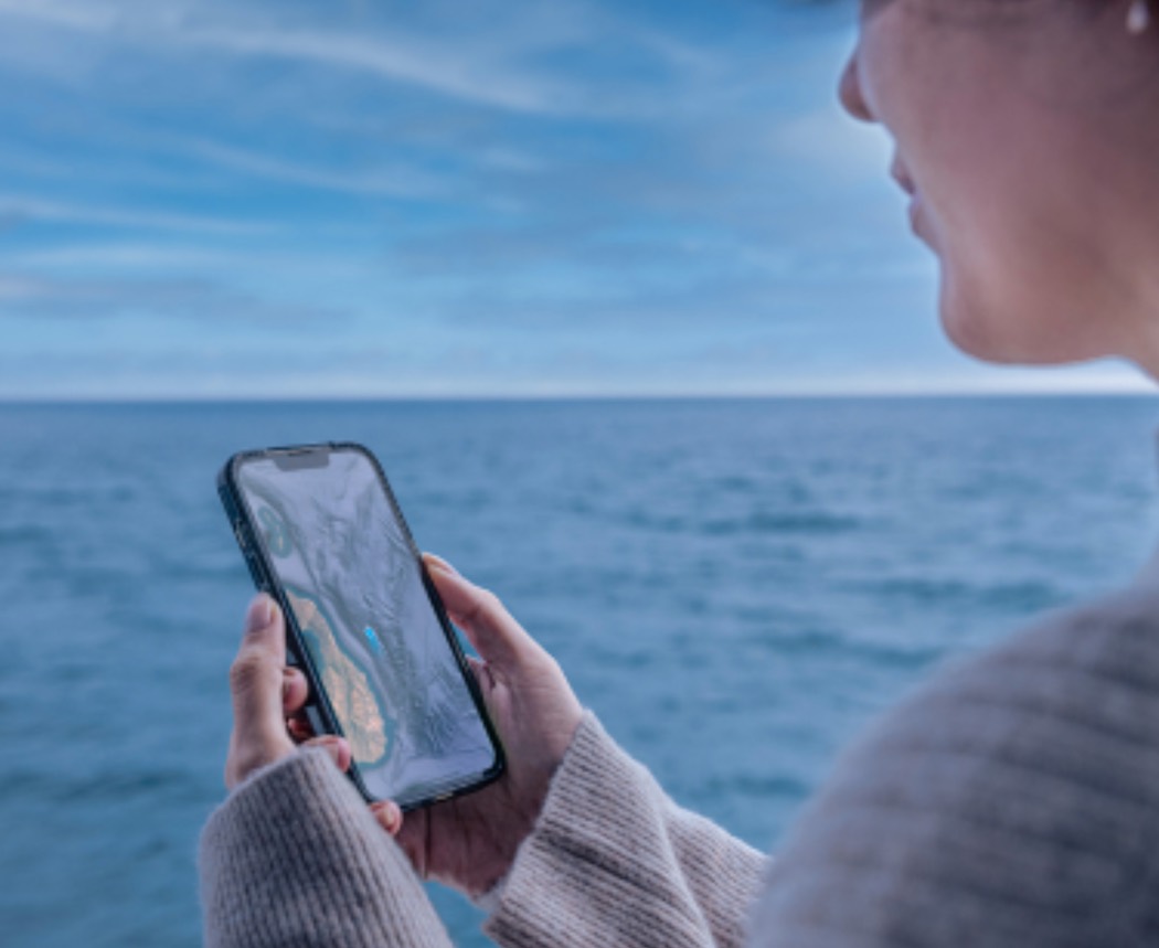 600万人以上のユーザーが利用する衛星経由の携帯電話通信サービス「Starlink Direct to Cell」を海上で使う女性の写真